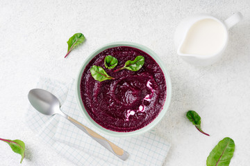 Beetroot cream soup in bowl on white stone background. Detox beetroot puree with chard leaves. Dieting, clean eating, slimming, vegetarian food concept