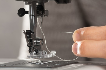 hands insert a thread in the sewing machine