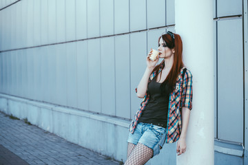 hipster girl drinks coffee near shopping center