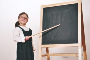A happy girl dressed as a teacher in front of a small blackboard, smiles. Concept of: educational, school, business and love for study.