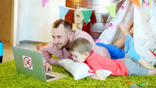 Little boy is watching cartoons with his father in the playroom