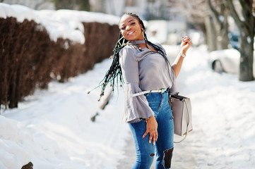 Rich african american girl with dreads and handbag at sunny winter day. Black stylish woman.