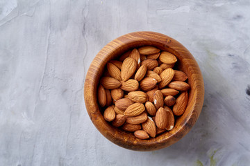 Bowl of almonds on white textured background, top view, close-up, selective focus.