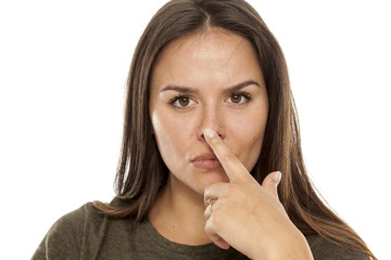 Naklejka premium Young woman toushing her nose with her finger on white background