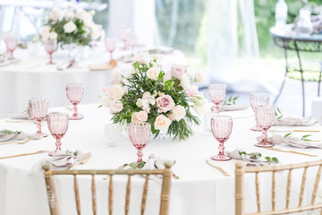 Beautiful table setting with crockery and flowers for a party, wedding reception or other festive event. Glassware and cutlery for catered event dinner.