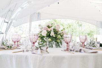 Beautiful table setting with crockery and flowers for a party, wedding reception or other festive event. Glassware and cutlery for catered event dinner.