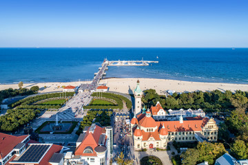 Sopot resort in Poland. SPA , old lighthouse, wooden pier (molo) with marina, yachts,  beach,  vacation infrastructure, park, promenade and walking people.  Aerial view. - obrazy, fototapety, plakaty