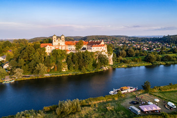 Fototapeta na wymiar Tyniec near Krakow, Poland. Benedictine abbey, monastery and church on the rocky cliff, Vistula river, tourist ship and unrecognizable people enjoying the picnic at a bonfire and outdoor restaurant