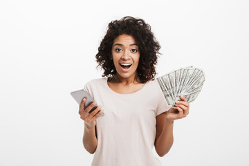 Happy winner american woman with afro hairstyle and big smile holding money prize dollar cash and...