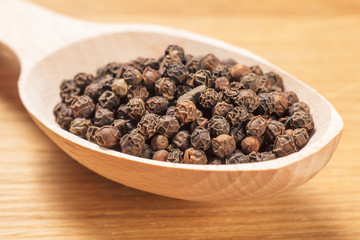 Close up wooden spoon with black peppercorn