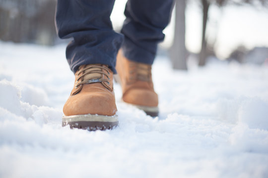 A man in red shoes and gray jeans is walking on the snow