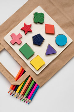 Still life educational toys for children, wooden multicolored educational game, puzzle for the development of skills and color pencils for the development of creativity on a white background.