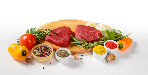 Raw beef steaks on a cutting board with spices
