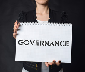 In the hands of a businessman a notebook with the inscription:GOVERNANCE