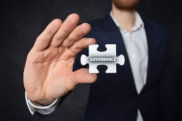 Businessman holding a puzzle with the inscription:GOVERNANCE