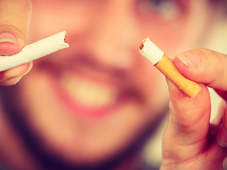 Smilling man is breaking a cigarette
