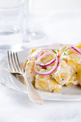 Fresh potato salad with mayonnaise dressing, onion and capers on white background