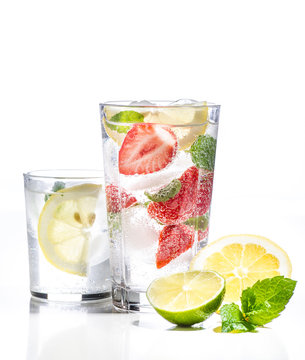 Glass of lemonade with lemon, lime and strawberries on white background