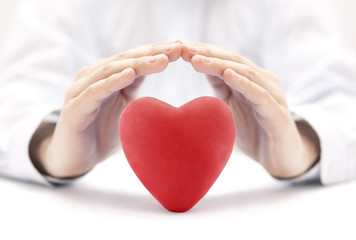 Red heart covered by hands. Health insurance or love concept 