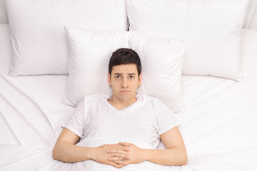 Pensive young man in bed