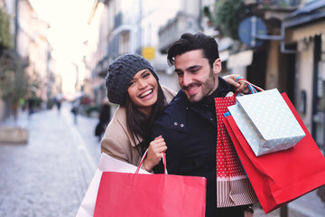 A couple of young engaged or friends, while they are shopping, having fun together, play and take pictures while they smile. Concept of: shopping, entertainment, friendship, love and leisure.