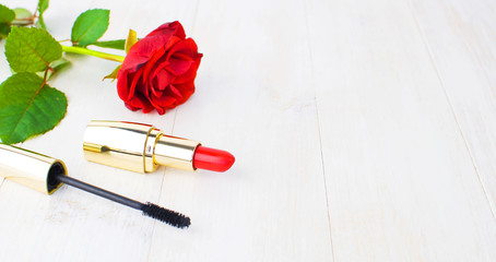 Obraz na płótnie Canvas Various cosmetic products for make-up with red roses on a white wooden background with copy space. Makeup Accessories Red lipstick Black mascara Selective focus.