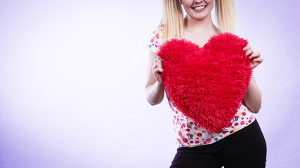 Happy woman holding heart shaped pillow