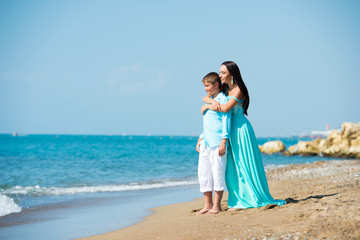 Fototapeta na wymiar happy family in a blue dress. Mother with baby on the beach