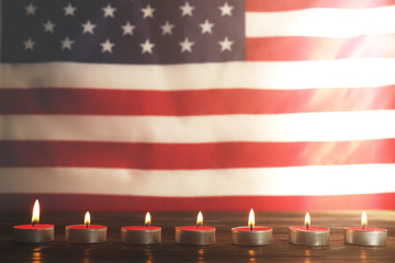 Mourning candles burning on USA American national flag background. Memorial weekend, patriot veterans day, 9/11 National Day of Service & Remembrance. Moment of silence concept. Close up, copy space.