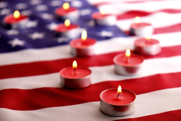 Mourning candles burning on USA American national flag background. Memorial weekend, patriot veterans day, 9/11 National Day of Service & Remembrance. Moment of silence concept. Close up, copy space.