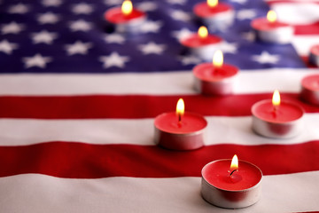 Mourning candles burning on USA American national flag background. Memorial weekend, patriot veterans day, 9/11 National Day of Service & Remembrance. Moment of silence concept. Close up, copy space.