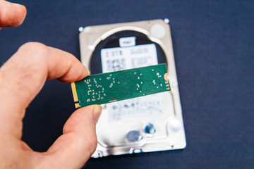 Man holding NVME PCIE fast ssd flash memory disk drive with old HDD