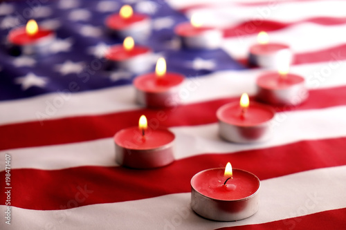 Mourning candles burning on USA American national flag background. Memorial weekend, patriot veterans day, 9/11 National Day of Service & Remembrance. Moment of silence concept. Close up, copy space.