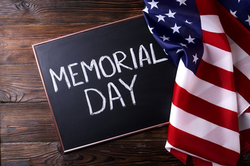 Fototapeta na wymiar Memorial day weekend text written on wooden black chalkboard with USA flag. United States of America stars & stripes patriot veteran remembrance symbol. Background, close up, copy space, top view.