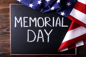 Fototapeta na wymiar Memorial day weekend text written on wooden black chalkboard with USA flag. United States of America stars & stripes patriot veteran remembrance symbol. Background, close up, copy space, top view.