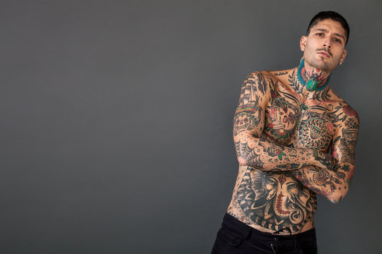 Handsome bare-chested tattooed man with arms crossed