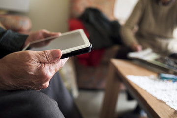 old man using a tablet and old woman reading