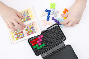 Hands of the child collect a color puzzle on a white background using the instruction