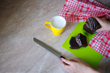 Вкусный завтрак с шоколадным кексом. Кекс с молоком на мраморном столе. Нарезаем кекс ножом на кухонной доске.
