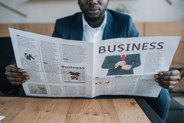 partial view of african american businessman with newspaper in cafe