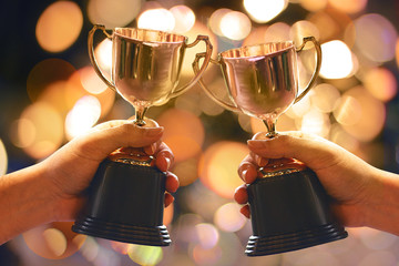 Two winners show trophy with abstract bokeh light background