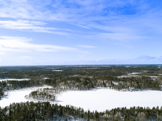 Aerial drone view of a winter landscape. Snow covered forest and lakes from the top. Sunrise in  nature from a birds eye view. Aerial photography. Aerial photo. Quadcopter. Winter road