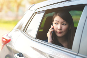 Young business woman is using a phone in a car