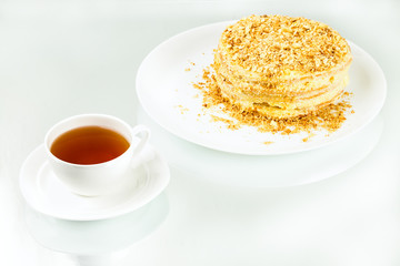 cup of tea, puff homemade cake with custard and biscuit crumb on white background