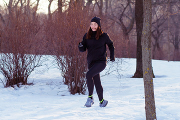 Fototapeta na wymiar young woman athlete in black sport suit run in winter park