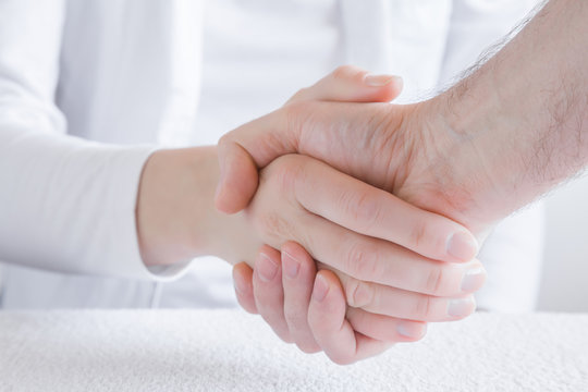 Patient grateful shaking hands with his doctor. Visit to physician at office. Medicine, healthcare and trust concept.