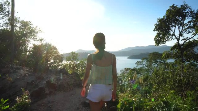 Asian woman walking towards the ocean to look at the scenic view. Travel lust adventure in tropical surroundings.
