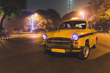 Yellow classic taxi service at Kolkata airport parking at night