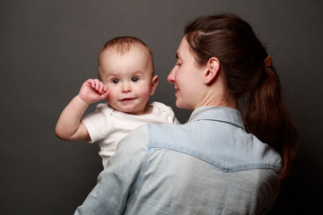 Mother and child hugging over gray background. Motherhood