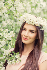 Fototapeta premium Beautiful Female Face Closeup. Beautiful smiling woman in spring flowers garden background